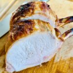 Herb and garlic brined pork rib roast cut into chops on a cutting board.