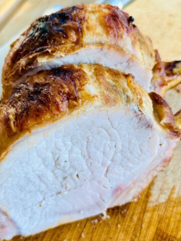 Herb and garlic brined pork rib roast cut into chops on a cutting board.