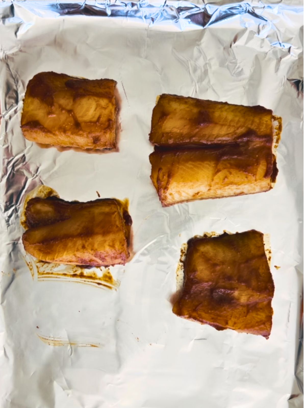 Four miso marinated sea bass fillets partially baked on a cookie sheet.