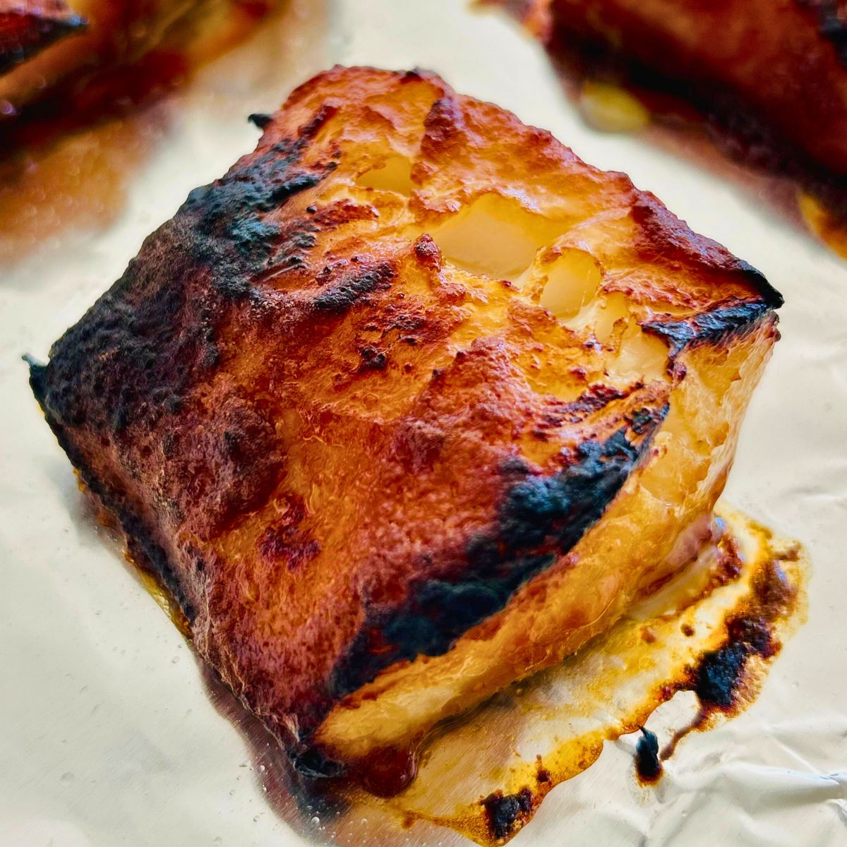 A serving of broiled miso marinated Chilean sea bass on a foil-lined sheet pan.