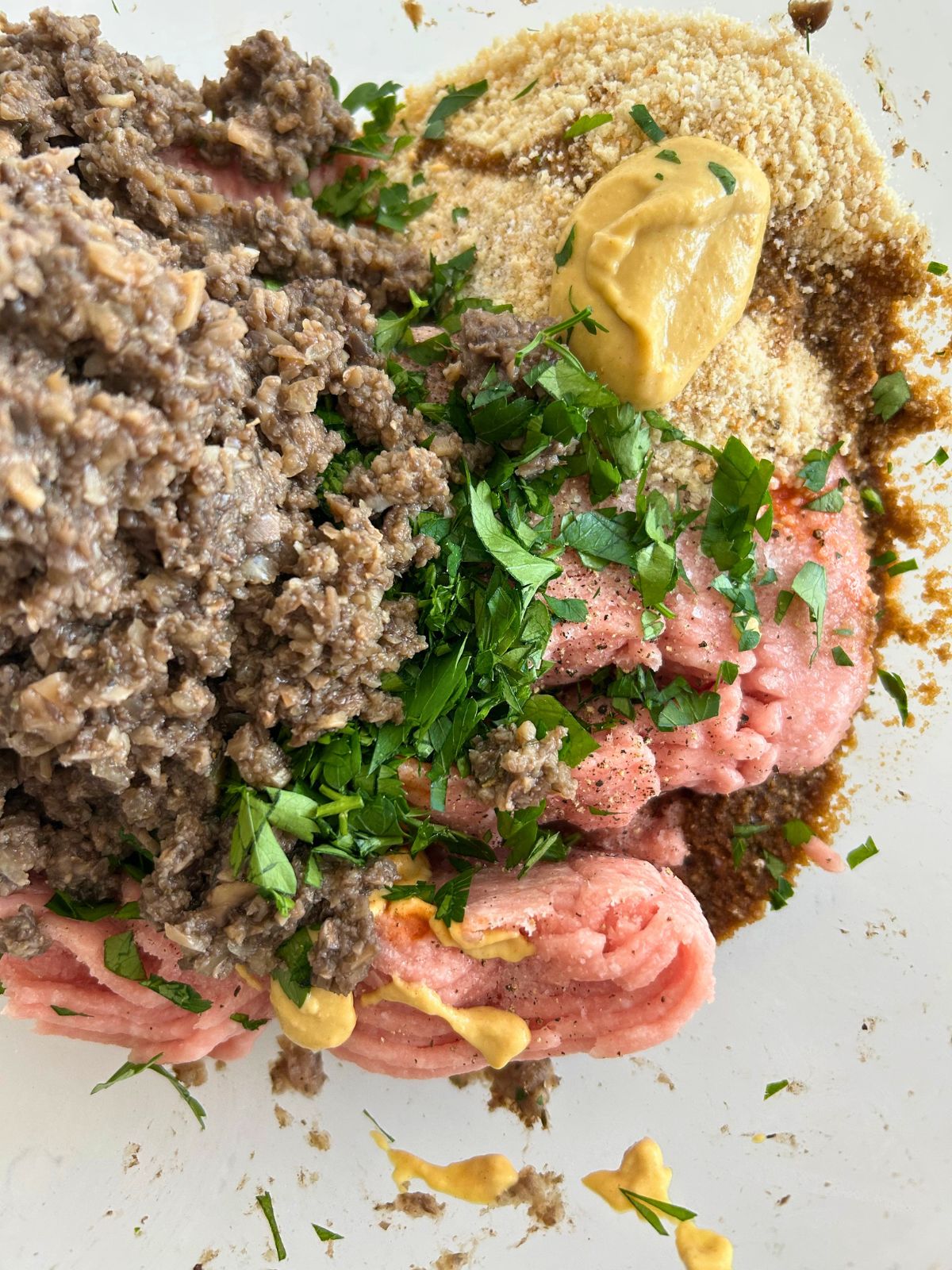 Ground turkey, cooked mushrooms mixture, and the rest of the meatloaf ingredients in a glass mixing bowl.
