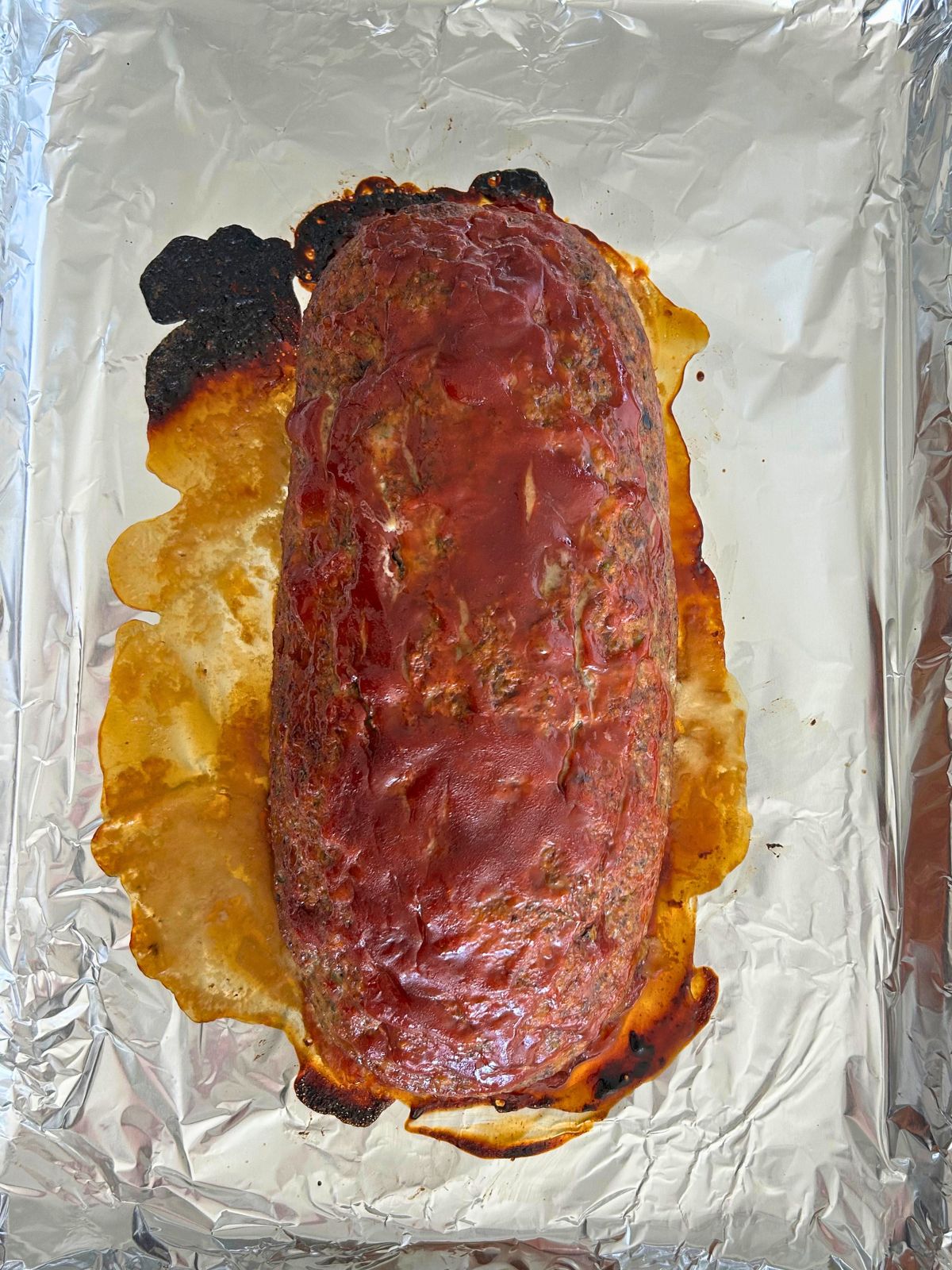 Turkey meatloaf with a sweet tangy glaze is fully cooked on a foil-lined rimmed baking sheet.