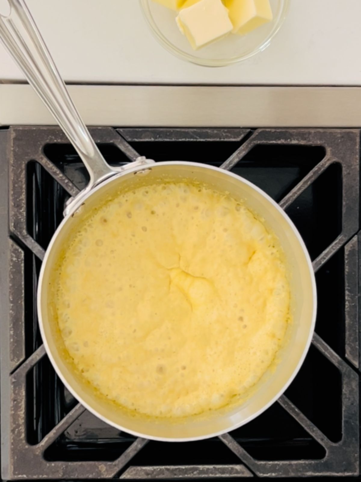 Cream, white wine, curry paste, and turmeric are boiling and reducing in a saucepan.