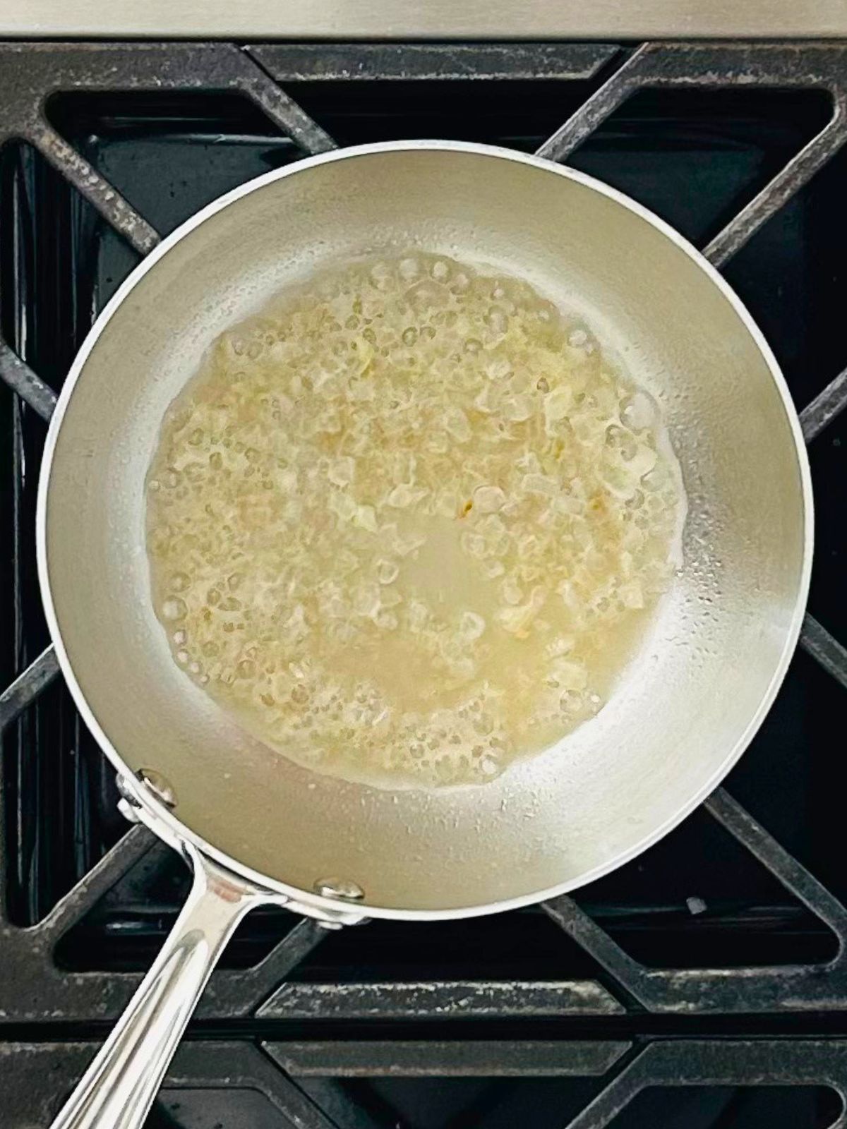Sake reducing with shallots in a stainless steel skillet.