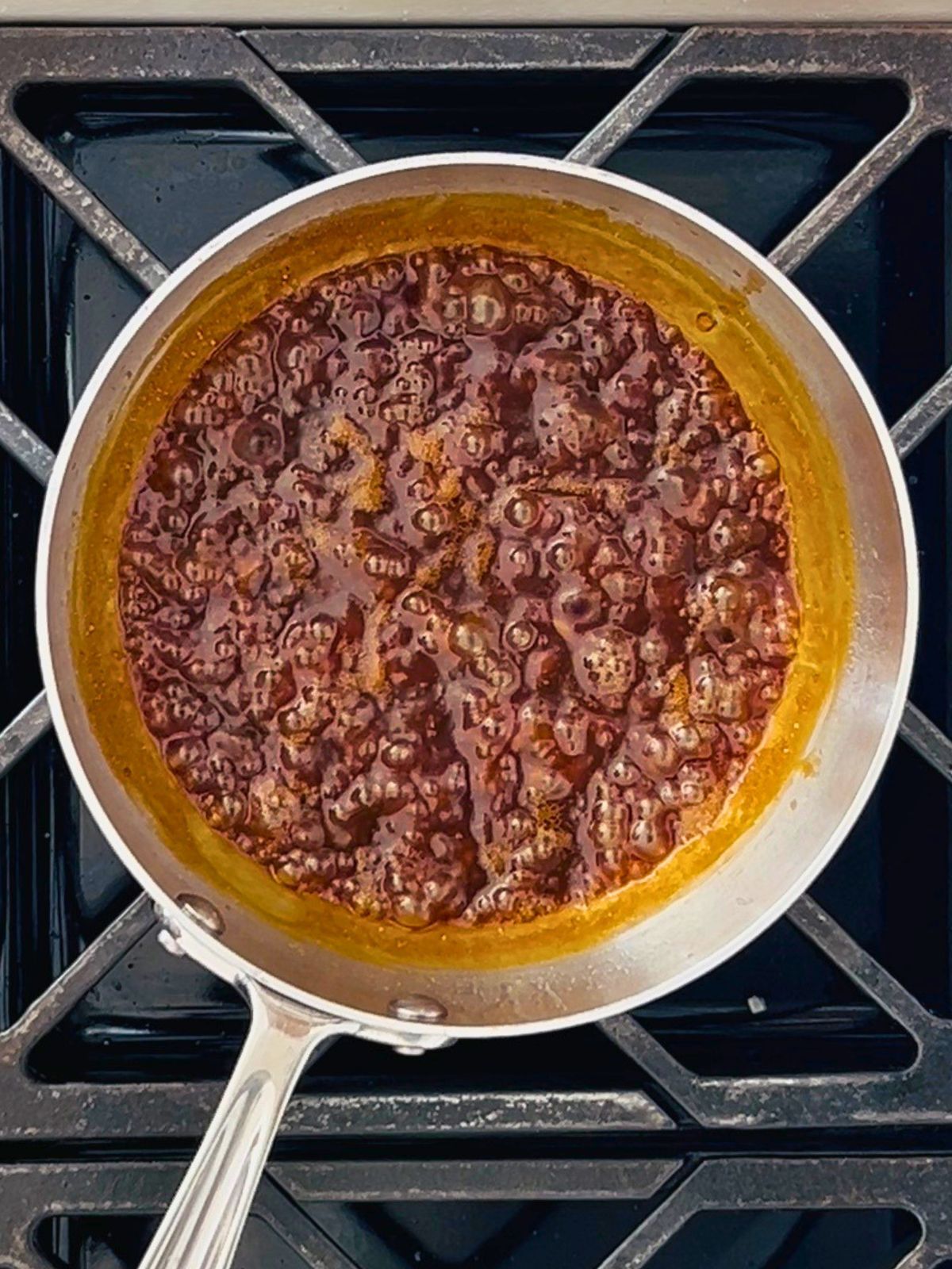 Miso butter sauce reduction bubbling in a stainless steel skillet on a gas stovetop.