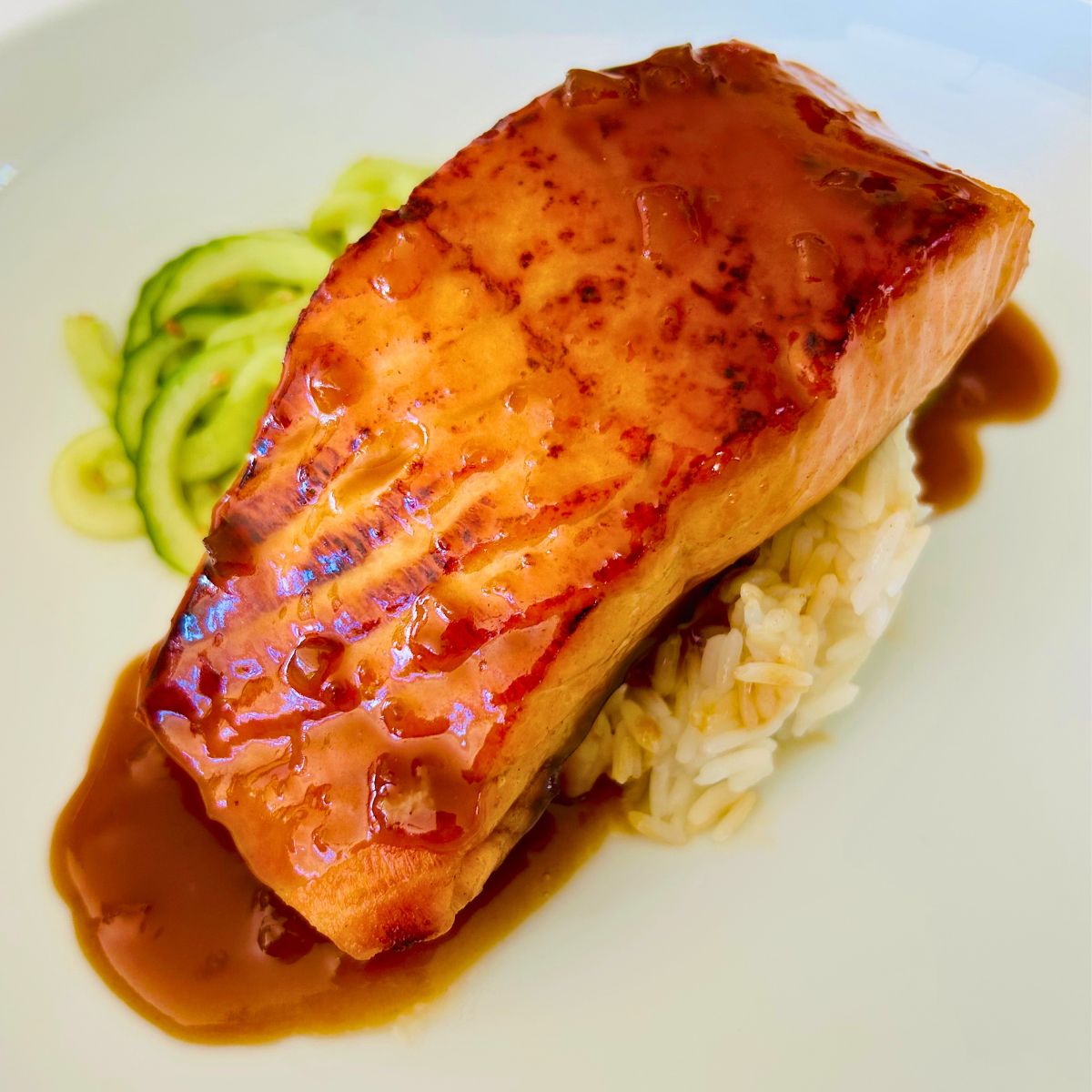Miso butter sauce drizzled over seared salmon, rice, and cucumber noodles.