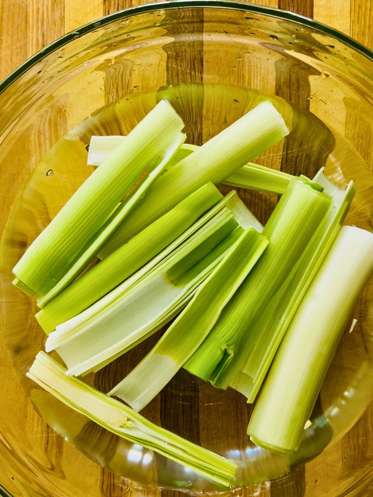 Cleaned leek pieces soaking in a glass bowl.