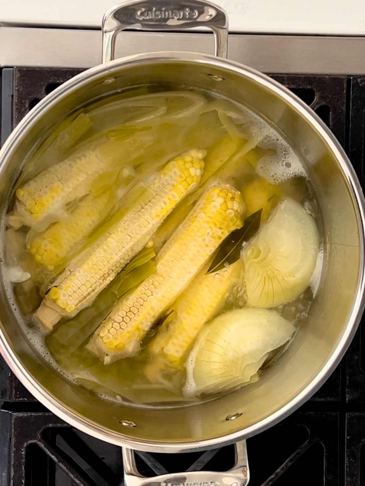 Corn cobs, leeks, onion, and bay leaves simmering in a stockpot to make homemade corn stock.