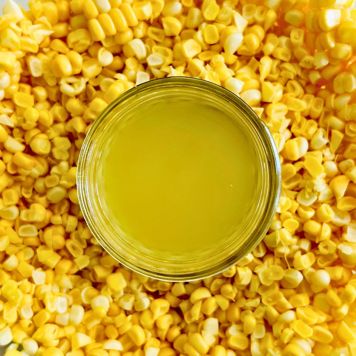 Corn stock recipe in a small mason jar nestled in a mound of corn kernels.