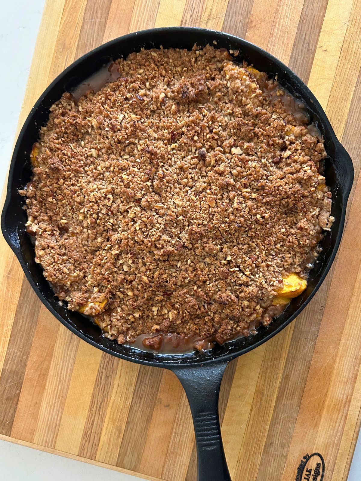 Freshly baked peach crisp with pecans in a cast iron skillet hot from the oven.
