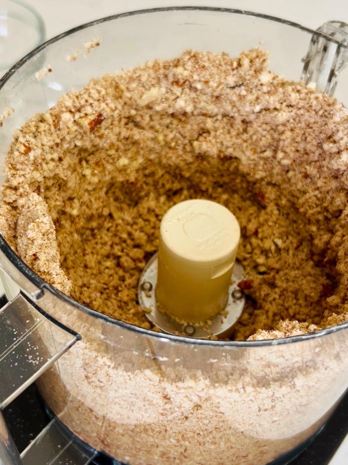 Completed peach crisp with pecans topping in a food processor showing the ideal crumbly, sandy texture.