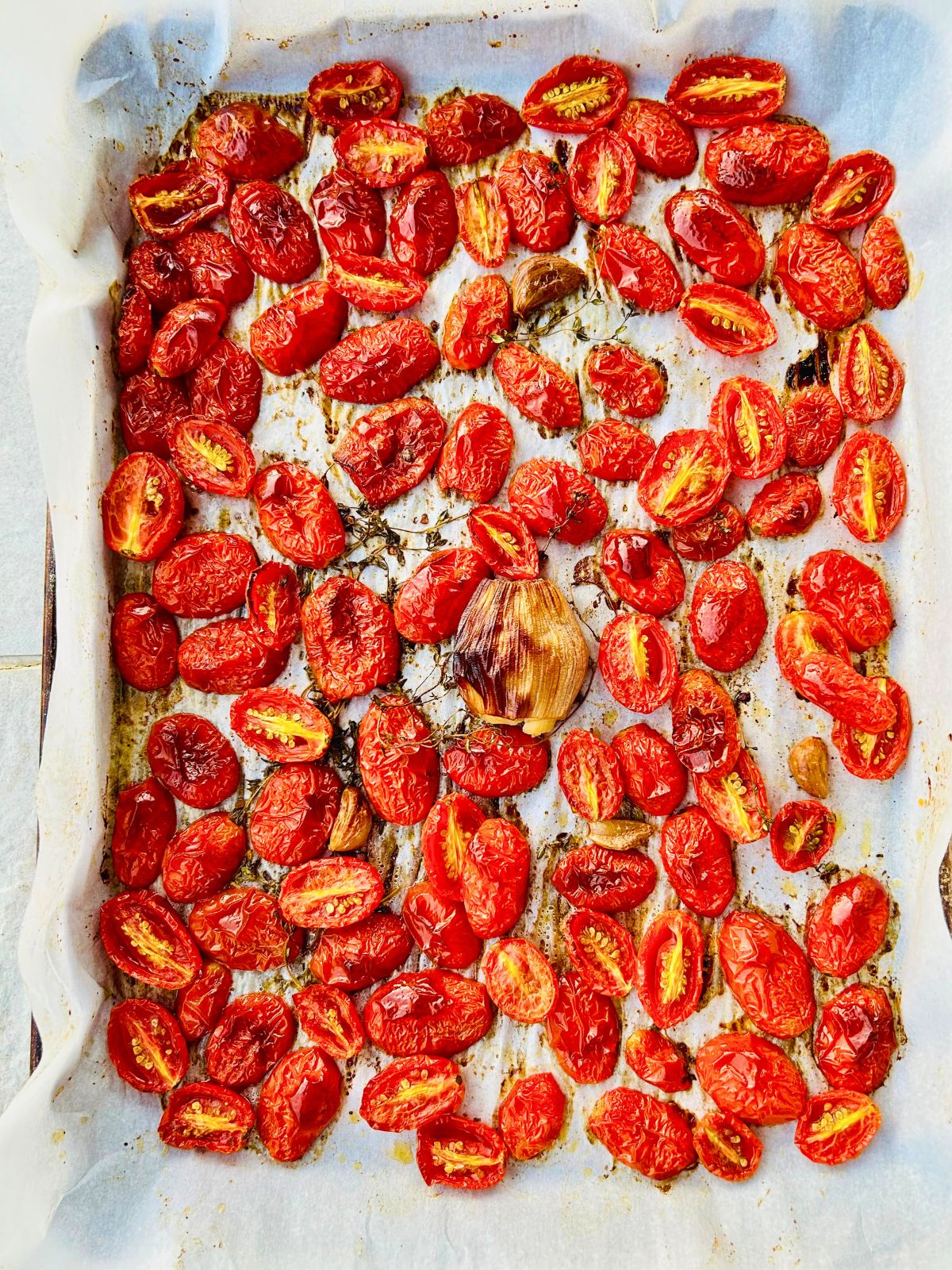 Roasted tomatoes caramelized on a parchment-lined baking sheet for homemade tomato paste.