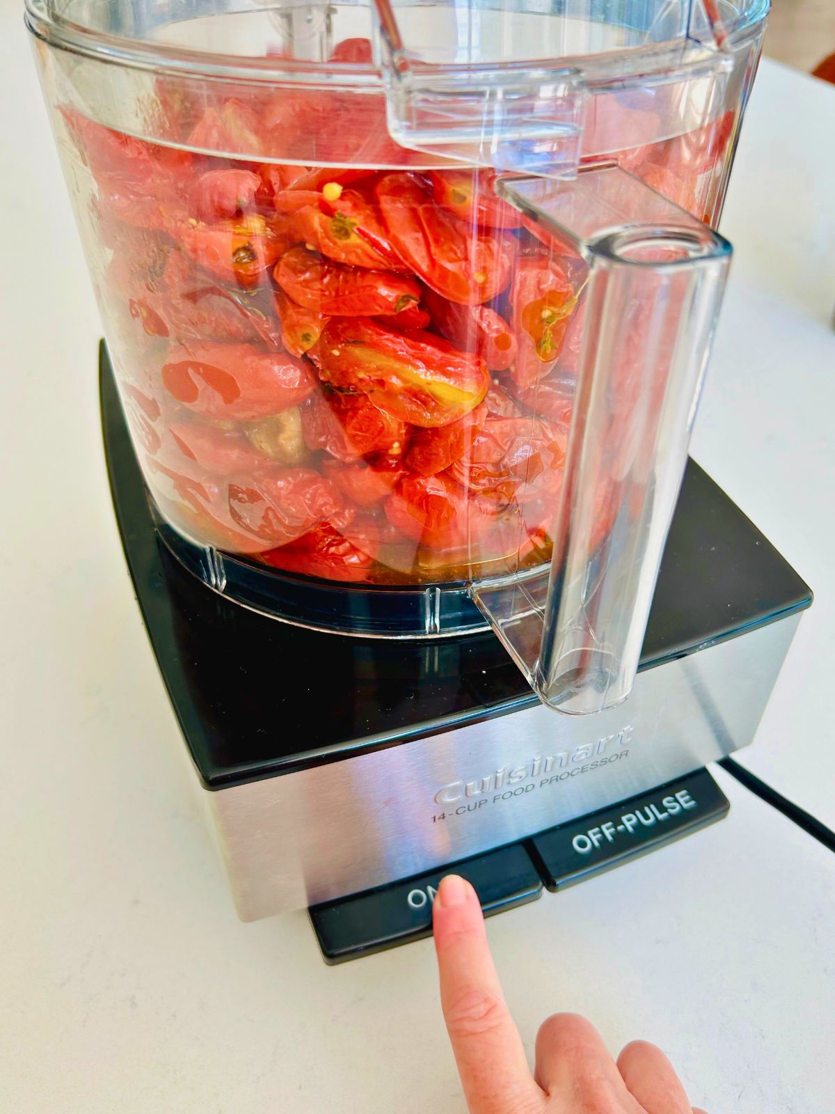 Roasted cherry tomatoes loaded into a Cuisinart food processor to blend into fresh tomato paste.