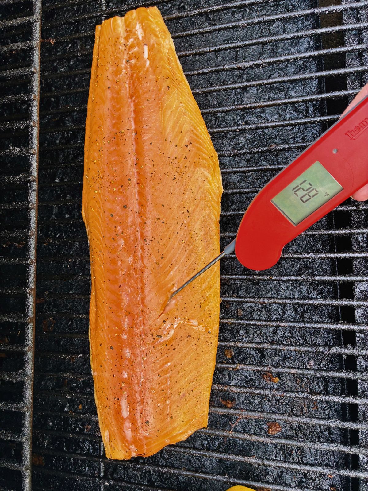 Grilled salmon on a Traeger with a meat thermometer showing it's done.