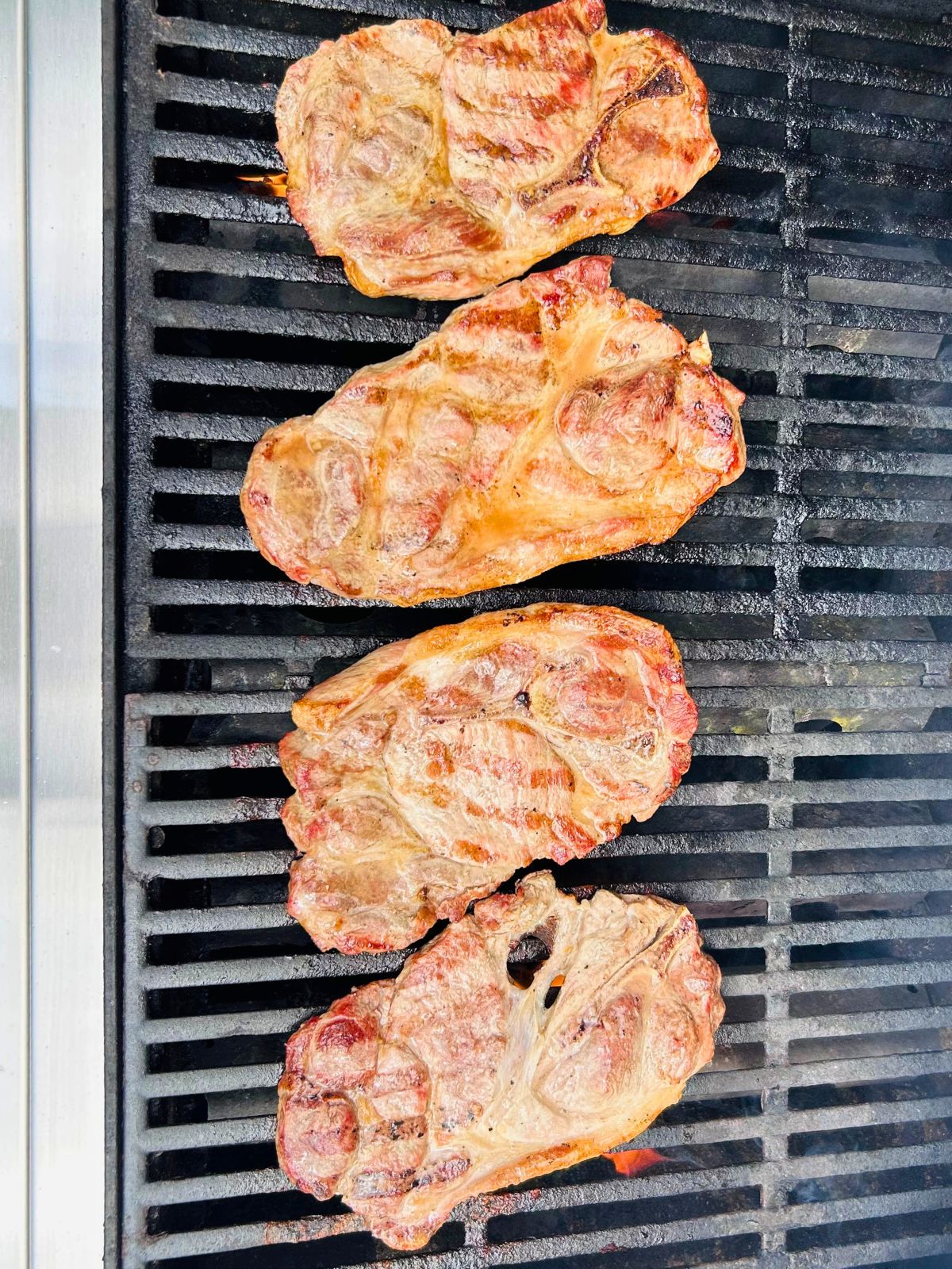 Pork steaks basted with butter, vinegar, and beer while cooking on the grill.