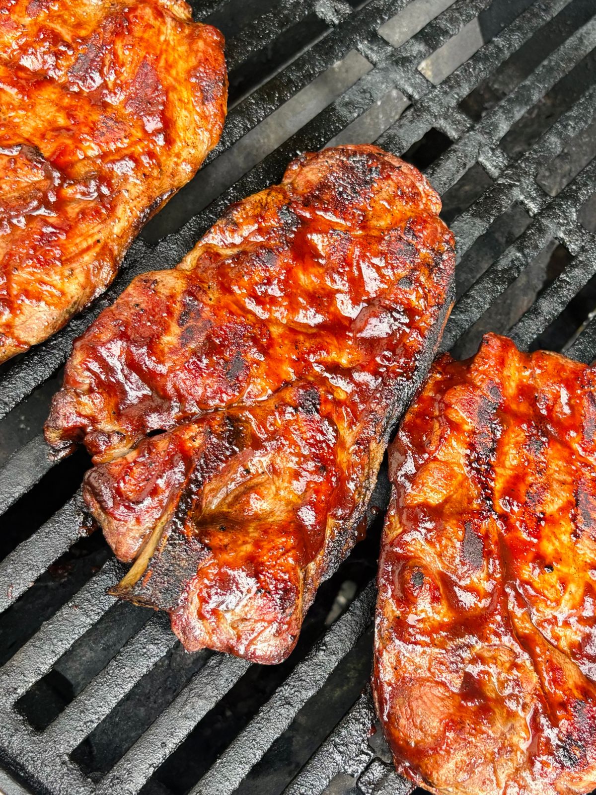Easy BBQ pork steaks basted with BBQ sauce and caramelizing briefly on the grill.