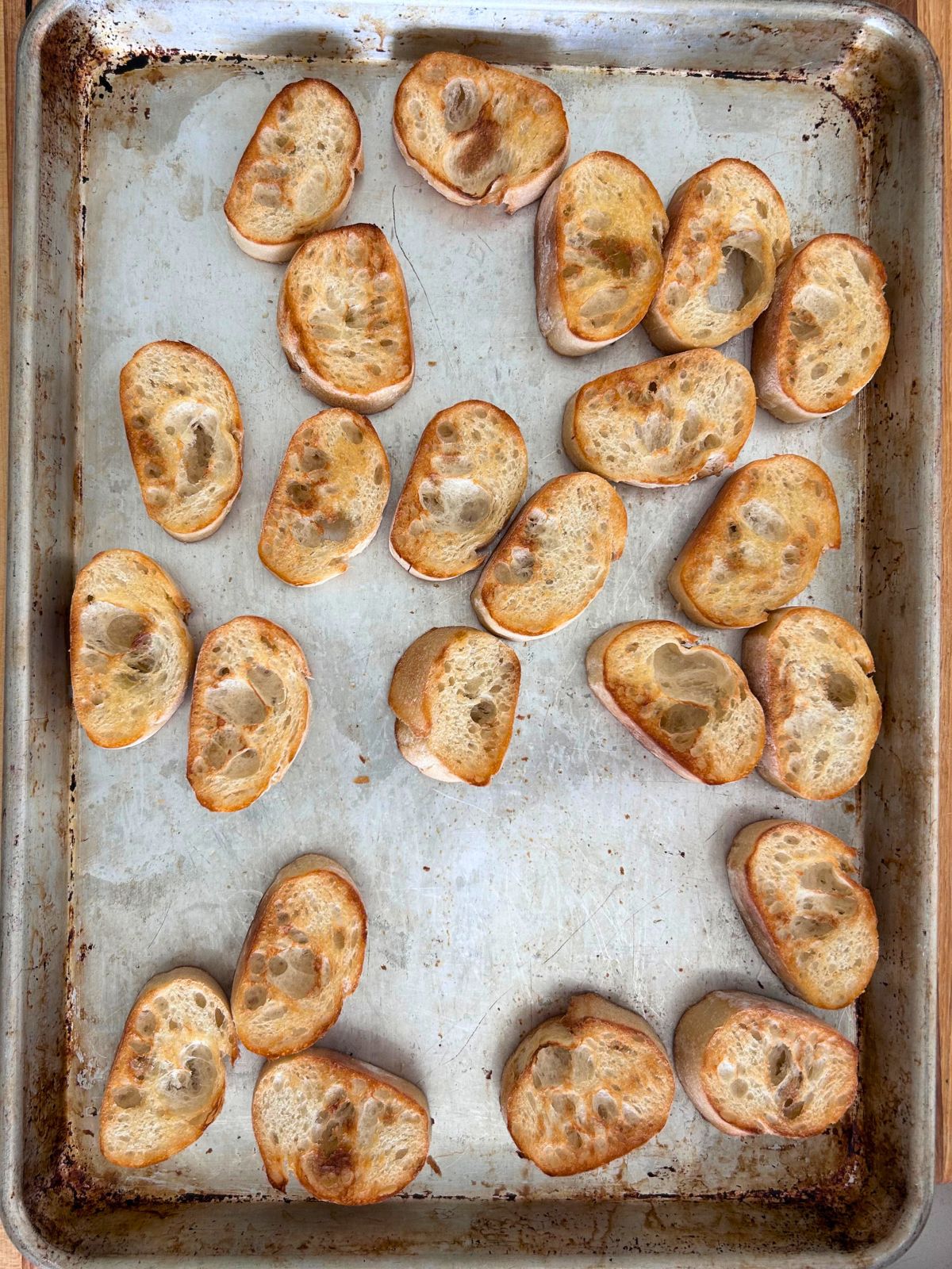 Sliced baguette toasted on a cookie sheet.
