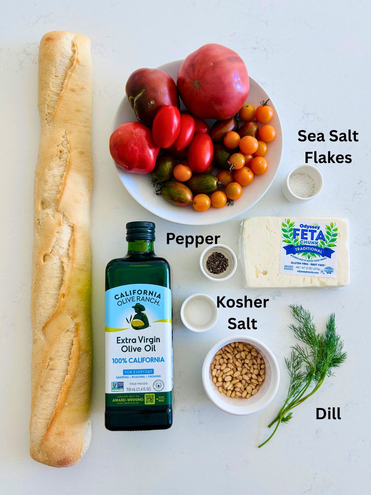 All of the ingredients needed to make fresh tomato salad with feta, pine nuts.