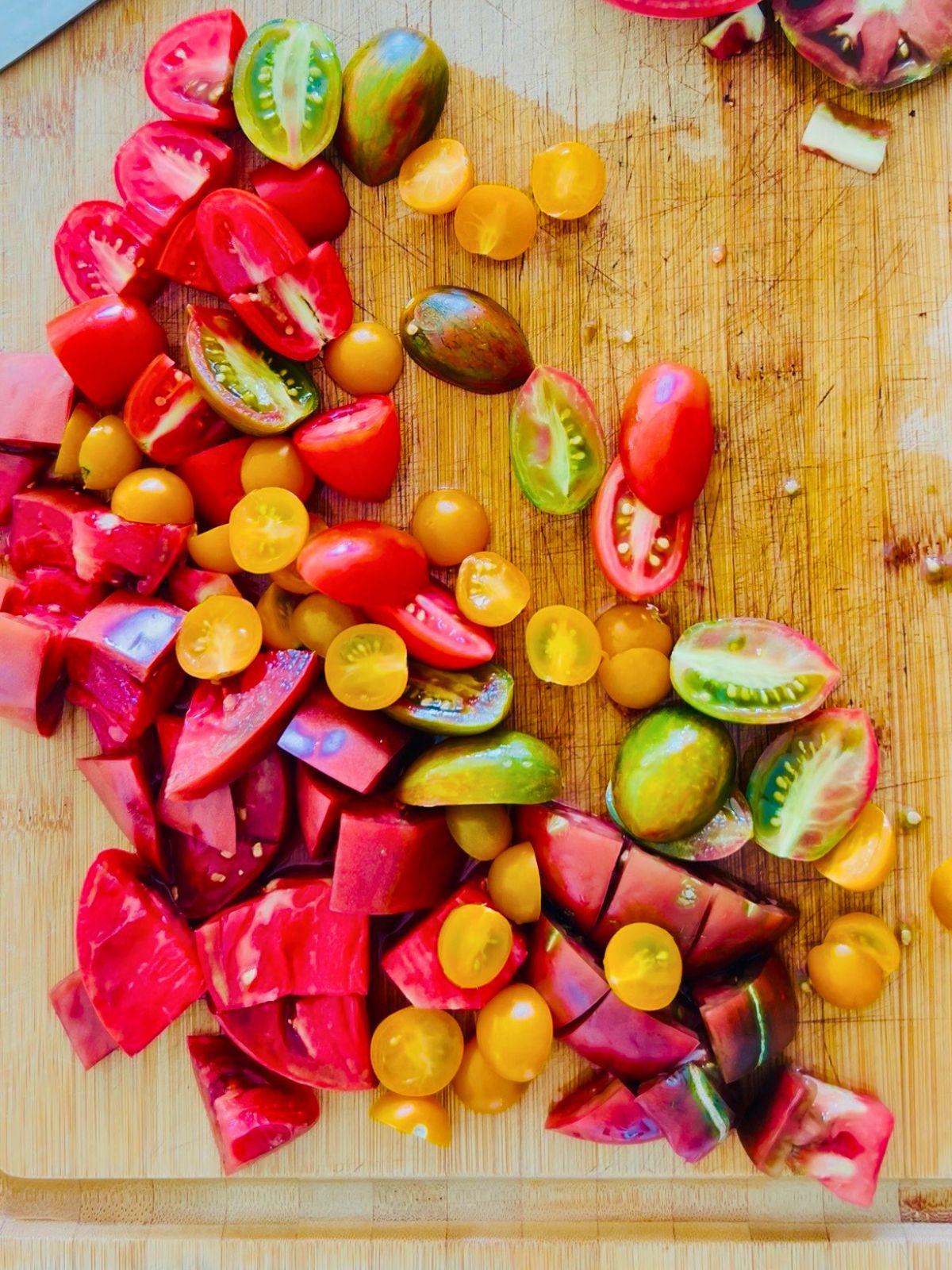 Bite sized pieces of garden tomatoes resting on a cutting board.