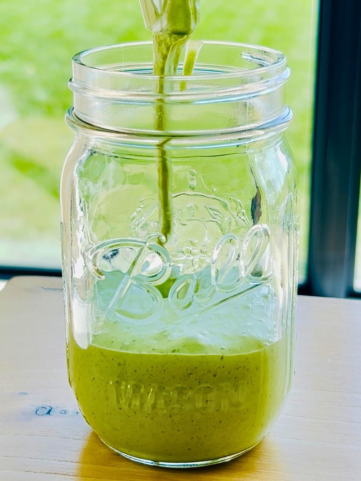 Jalapeño ranch is pouring into a mason jar.