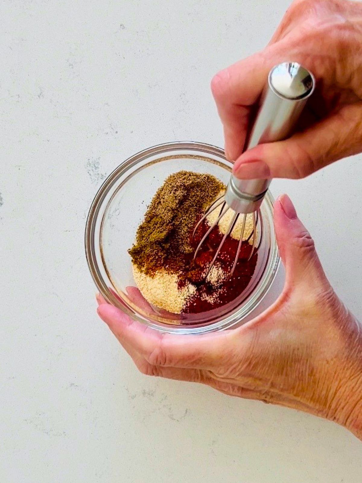 Taco seasoning ingredients are whisked in a small glass bowl.