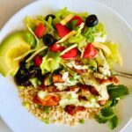 Chicken burrito bowls with jalapeño ranch and fresh toppings with a fork nestled on a white plate.