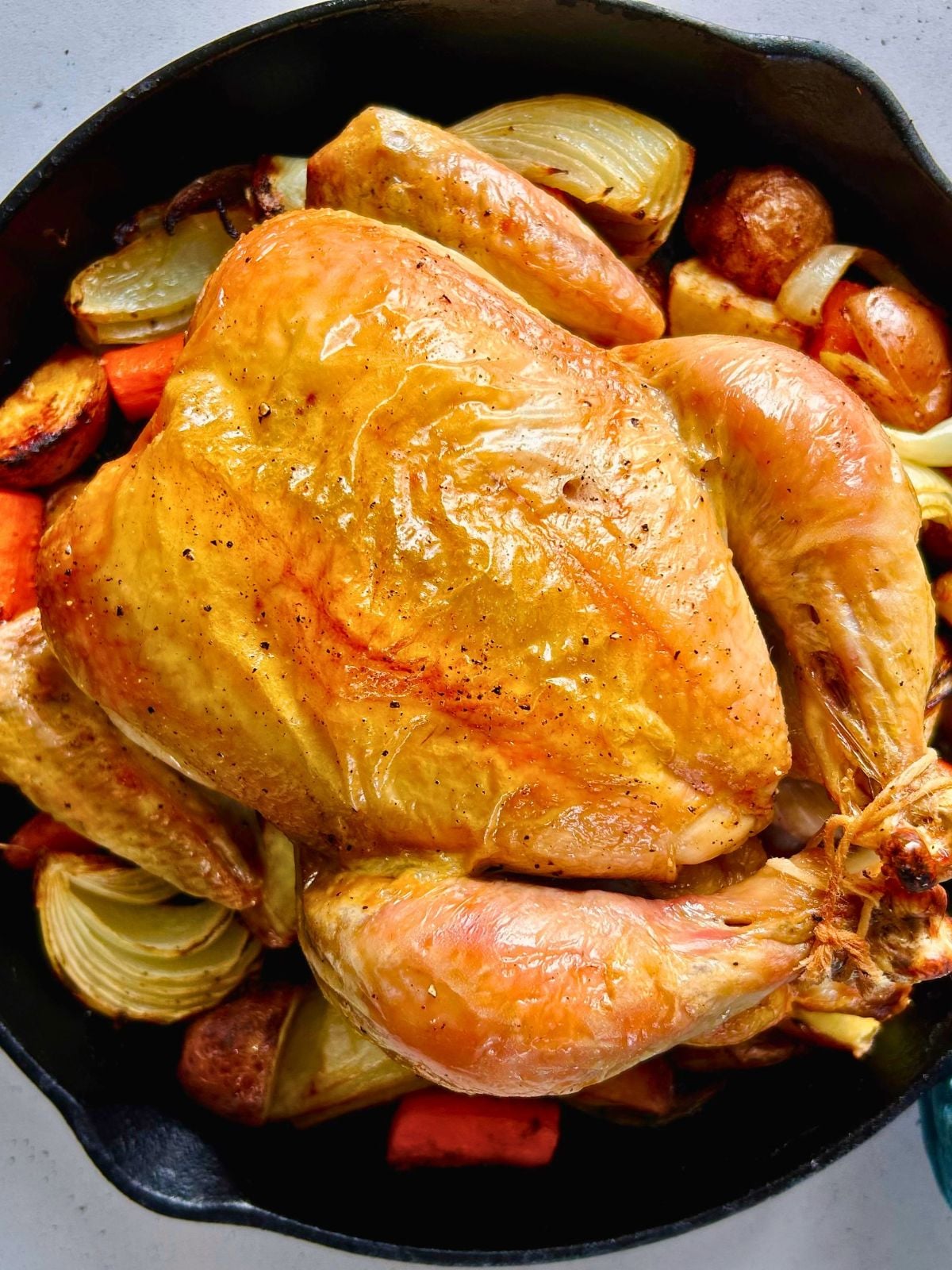 Juicy skillet roasted whole chicken with caramelized vegetables in cast iron.