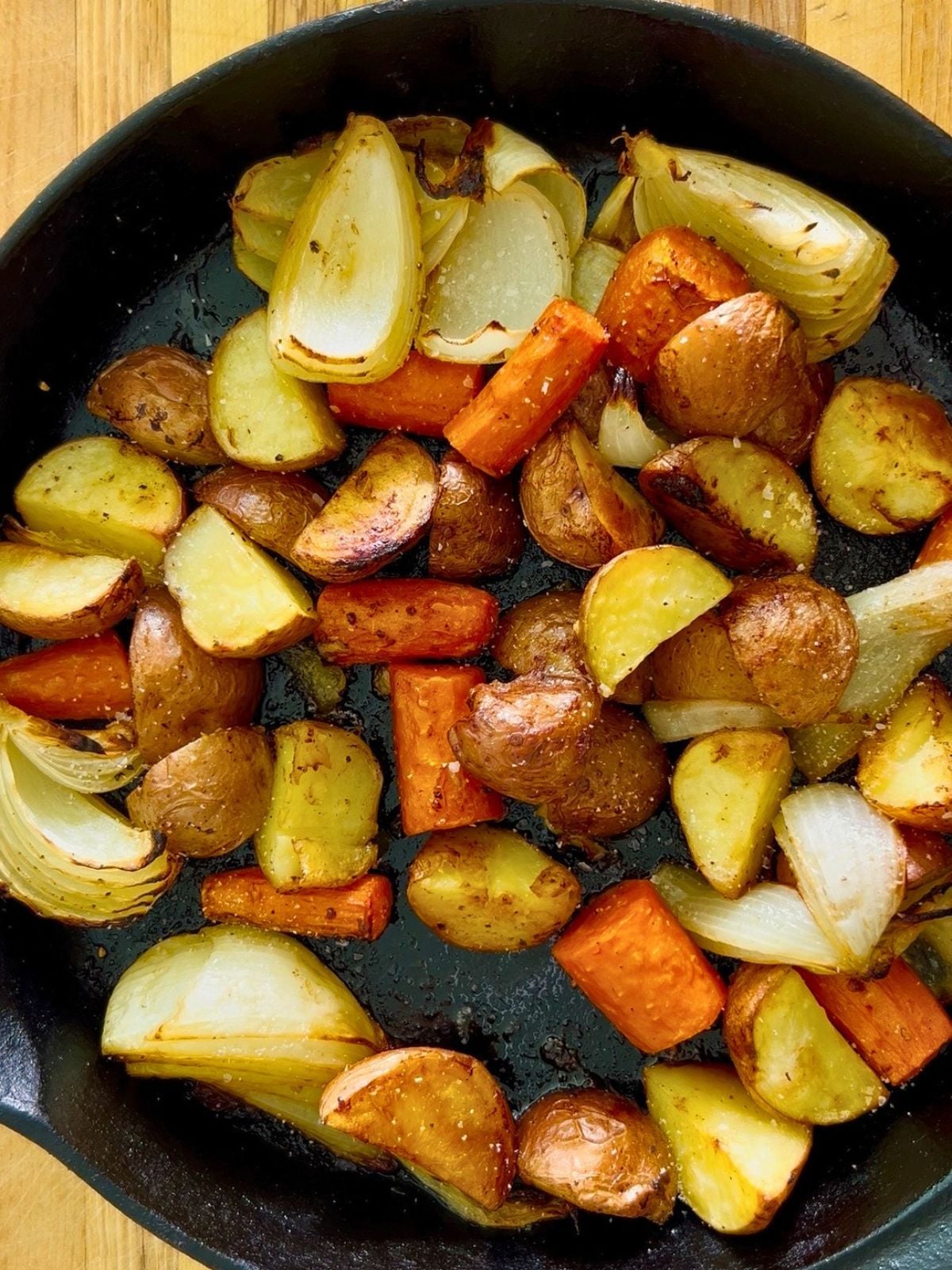 Caramelized potatoes, carrots, and onions in a cast iron skillet.