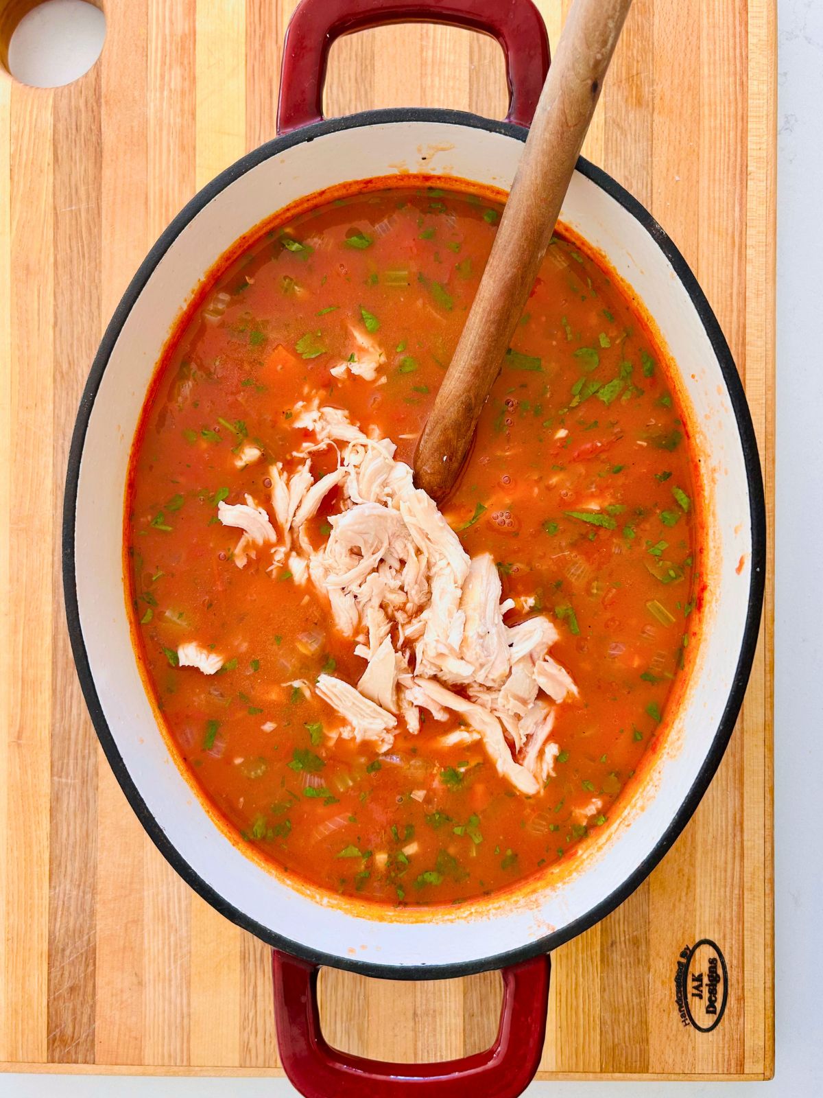 Chunks of moist chicken breast are stirred into a pot of Mexican chicken and vegetable soup.