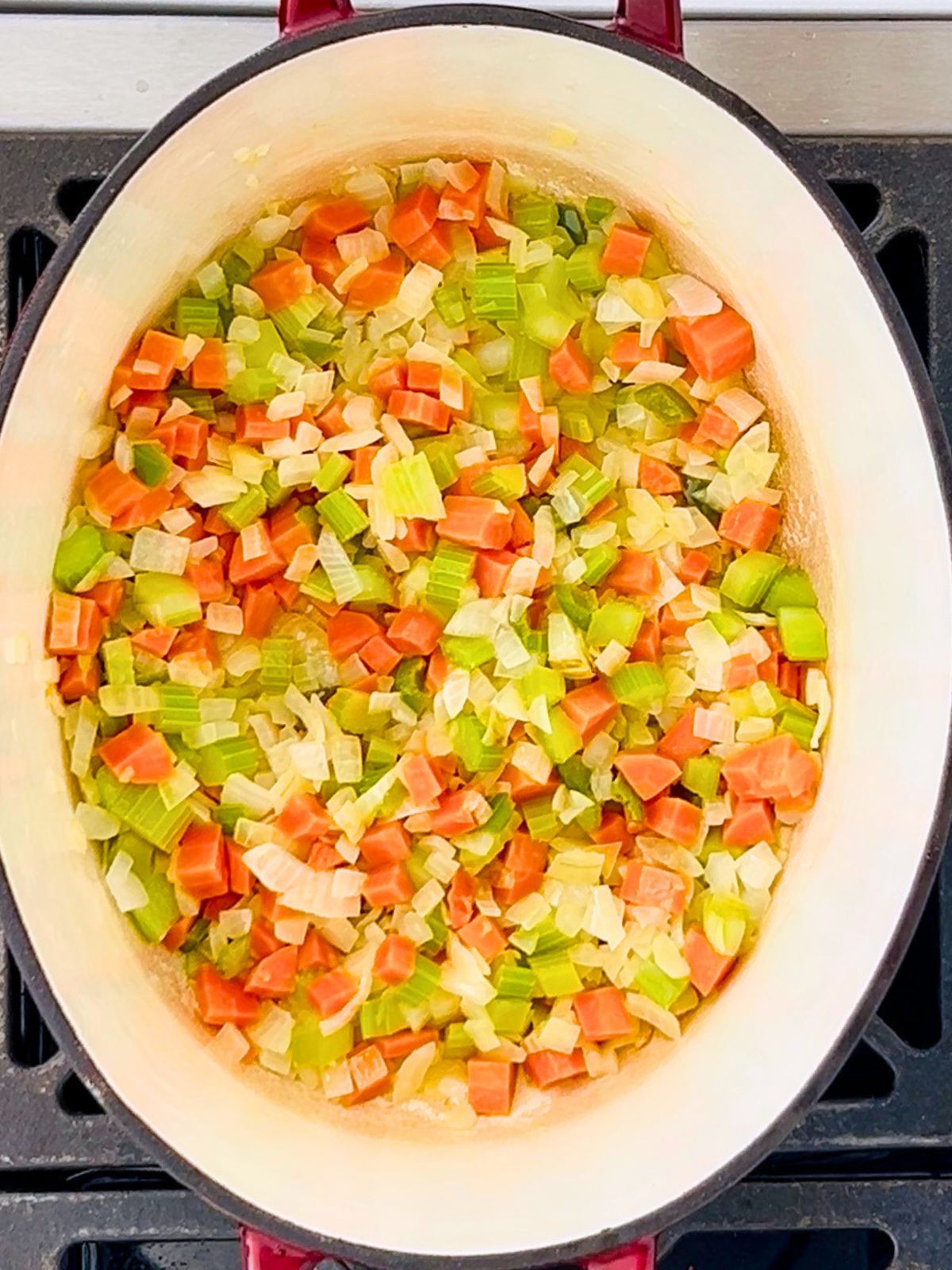 Softened chopped onions, celery, carrots, and jalapeno in an enameled pot over a burner.