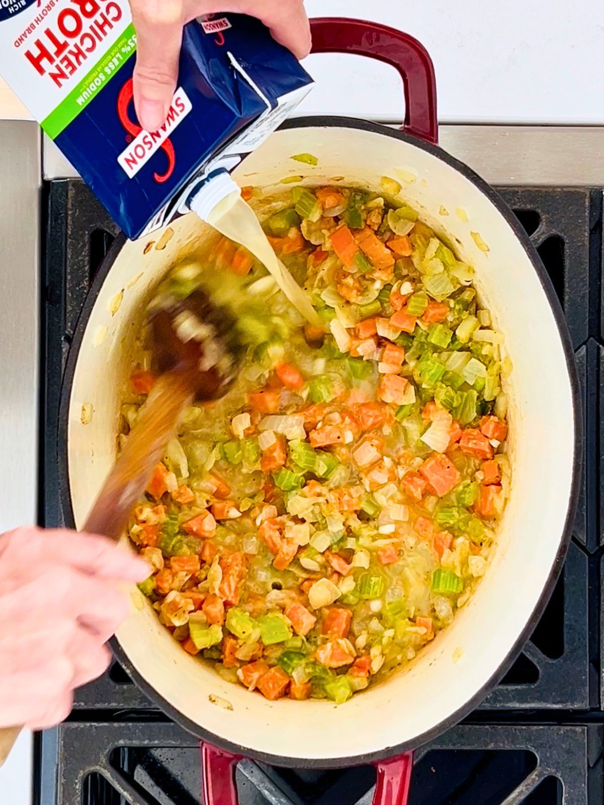 Chicken broth is stirred into a pot of vegetables over a burner for Mexican chicken and vegetable soup.