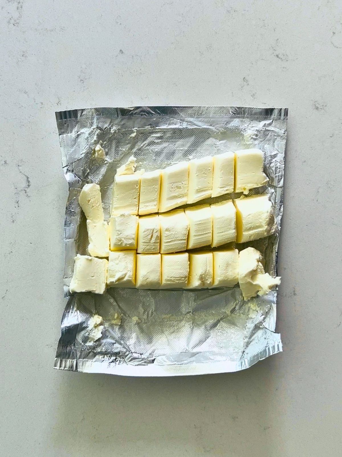 Cubes of cream cheese on top of an open foil wrapper.